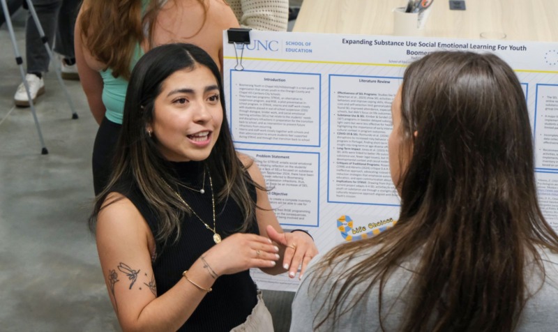 HDFS student presents their research poster to a classmate