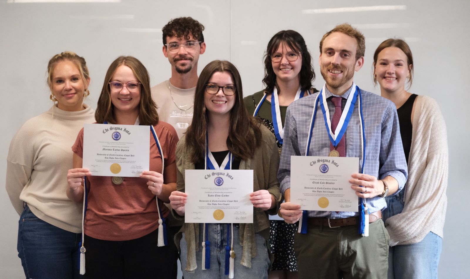 School counseling students pictured holding certificates.