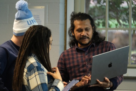 Three students looking at laptop collaborating