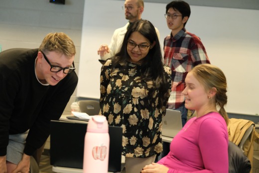 MEITE students present a project they are working on to a faculty member on a laptop