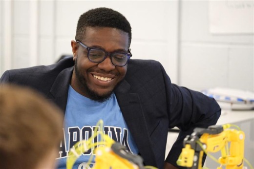 MEITE student Rich Gillman introduces a robotics project to a group of young students