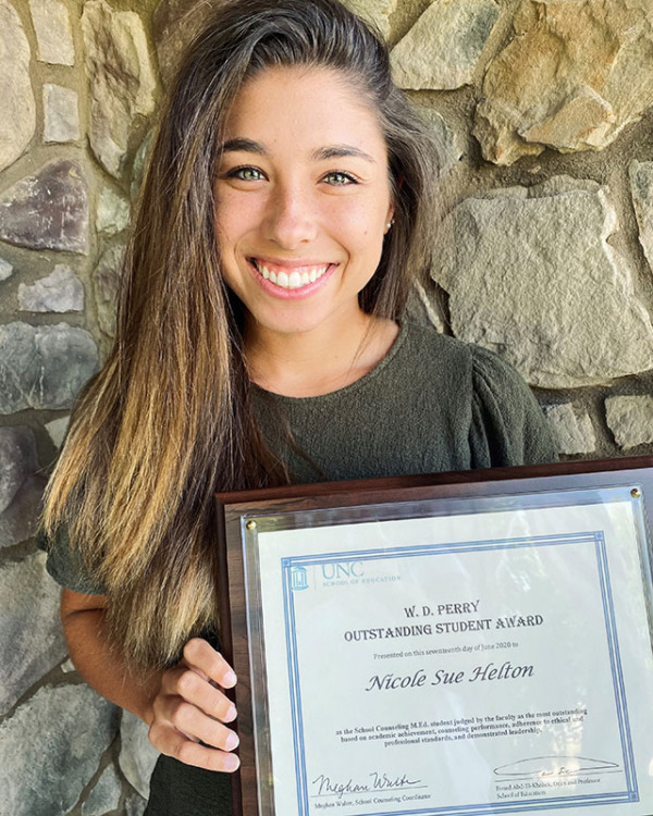 Nicole Hilton holds certificate for the W.D. Perry Award while standing in front of a rock wall