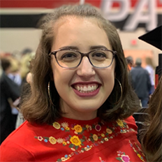 Portrait of Courtney Medina. Courtney is a white woman with brown hair wearing black glasses and a red shirt with flowers on it.