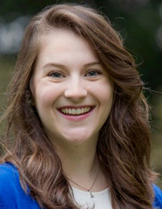 Portrait of Savannah Purdy. Savannah is a white woman with wavy brown hair. She is wearing a blue cardigan and smiling.