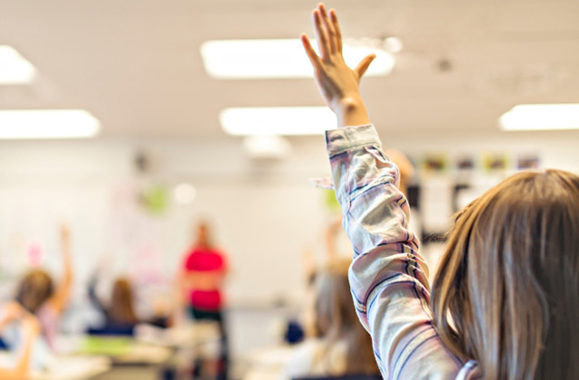 girl in classroom raising her hand