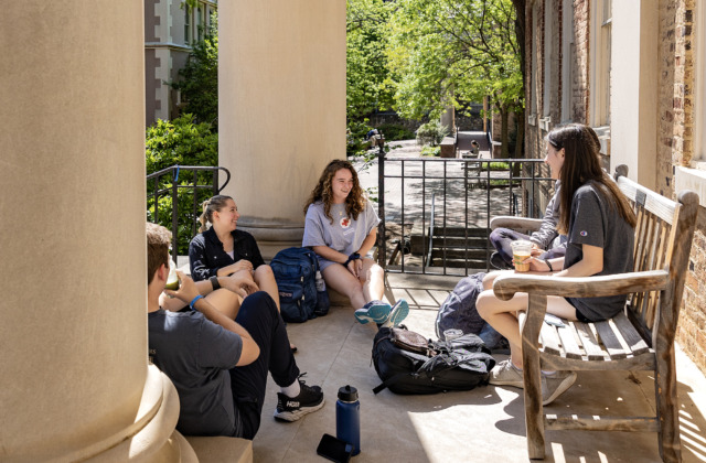 A group of students sitting in front of South Building while talking with each other.