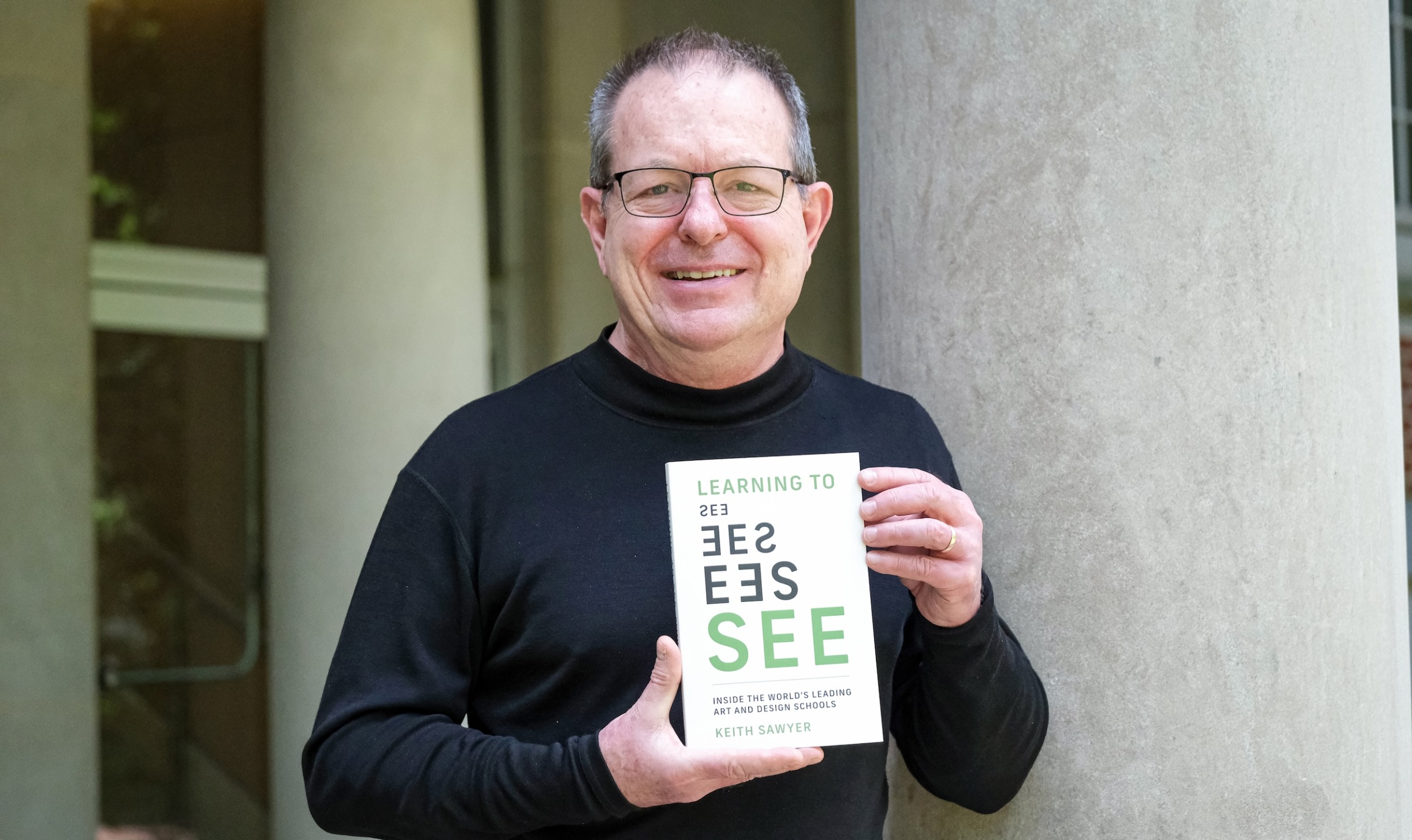 Image of Keith Sawyer holding a copy of his book, 