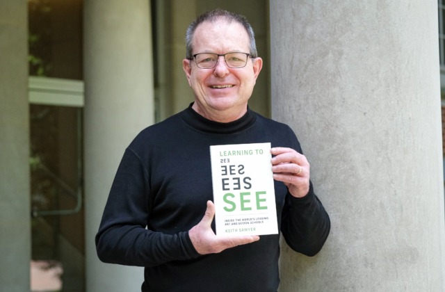 Image of Keith Sawyer holding a copy of his book, 