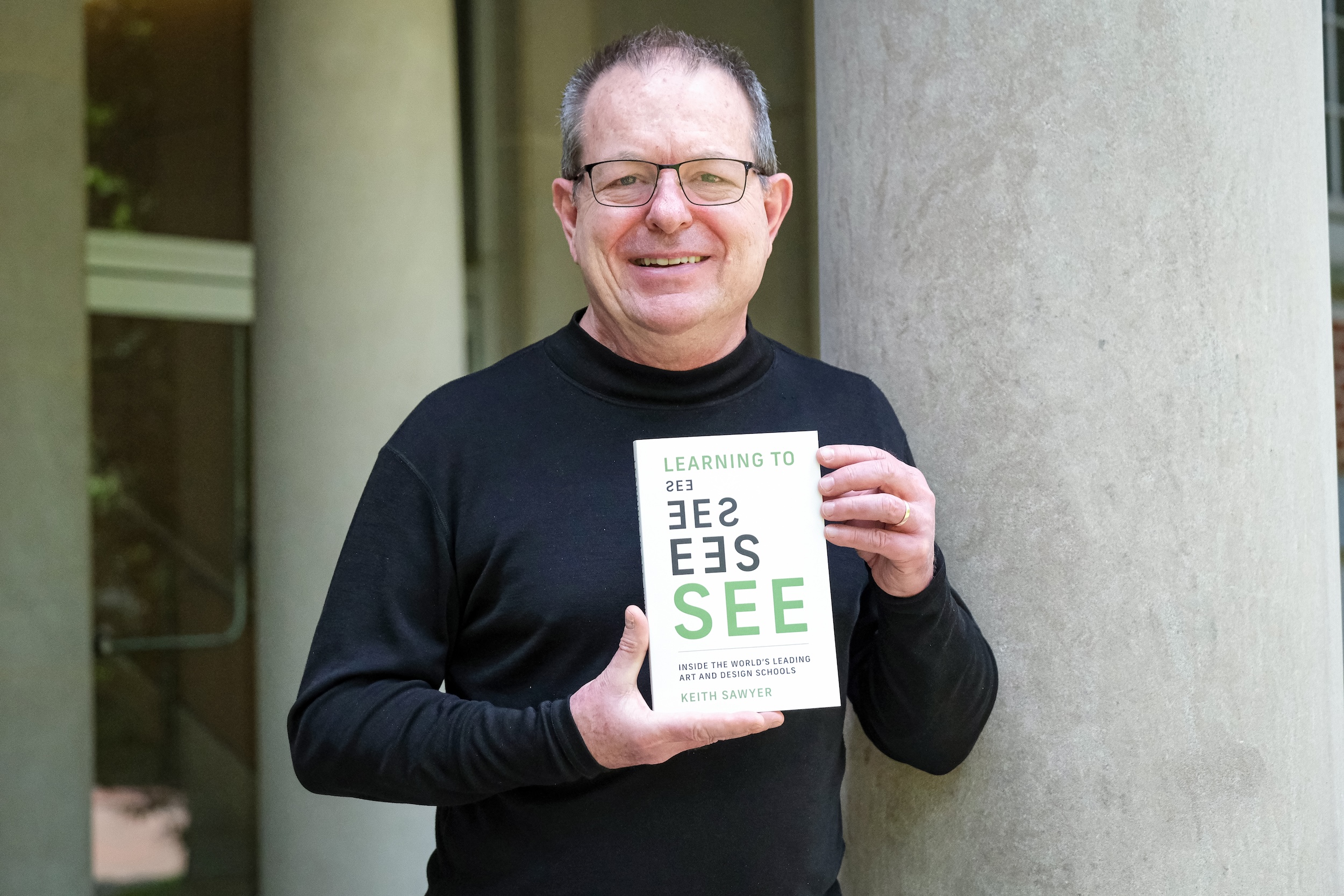 Image of Keith Sawyer holding a copy of his book,