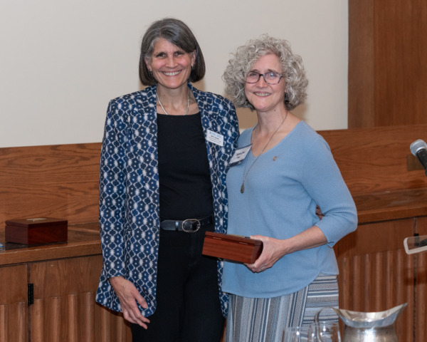 Dean Jill V. Hamm (left) and Whichard’s daughter, Jennifer Ritz (right), stand together smiling during the 2025 UNC School of Education Alumni Awards ceremony as she accepts the award on his behalf.