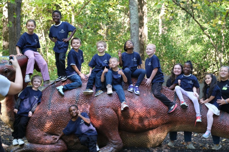 A group of CCA studentspose for a photo with the dinosaur statue at the Museum of Life and Science during their recent field trip.