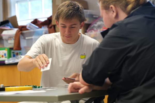 two students play a card game at a table.
