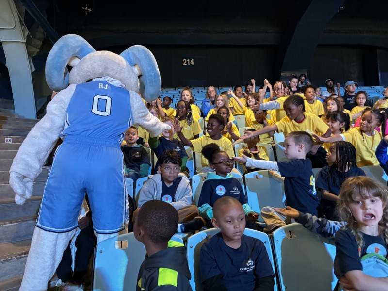 CCA students receive high fives and greetings from RJ during a UNC Women's Basketball game.