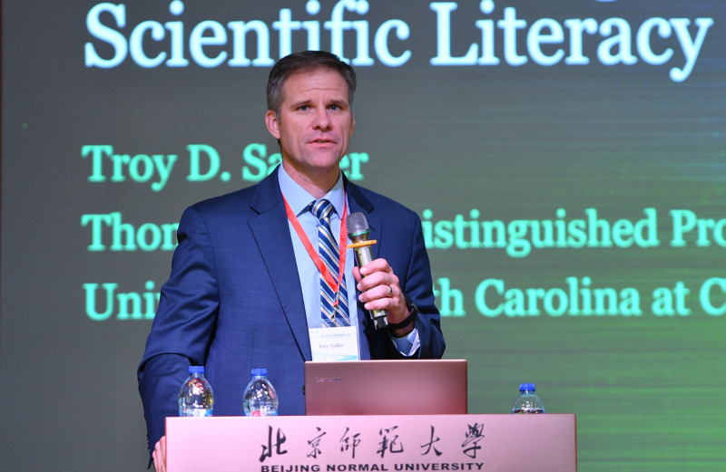 Photo of Troy Sadler holding a microphone at a podium