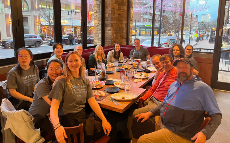 Image of Troy Sadler and current and former graduate students at a table in a restaurant