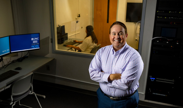 Image of Casey Calhoun standing front of lab assistant sitting at a computer.