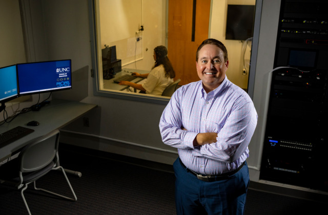 Image of Casey Calhoun standing front of lab assistant sitting at a computer.