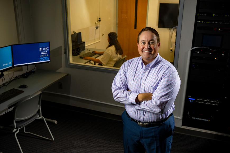 Image of Casey Calhoun standing front of lab assistant sitting at a computer.