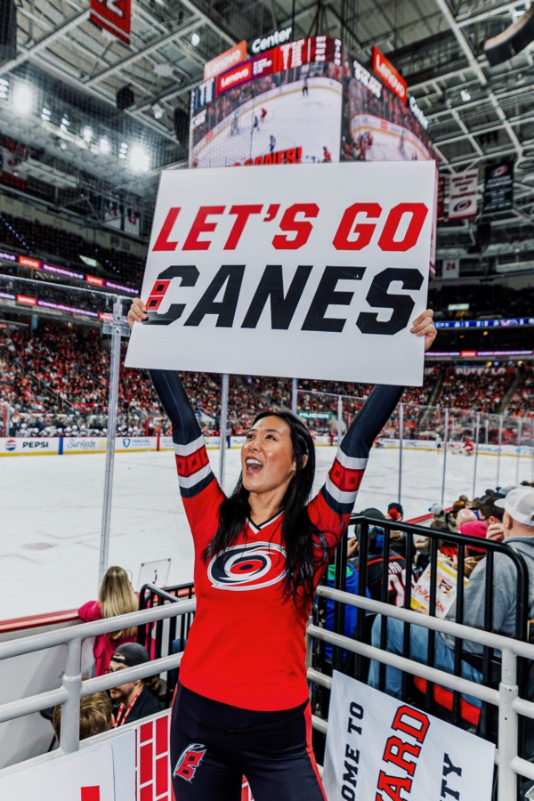 Maya Lin holds up a sign that says "Let's Go Canes" while energizing fans in the Lenovo Center.