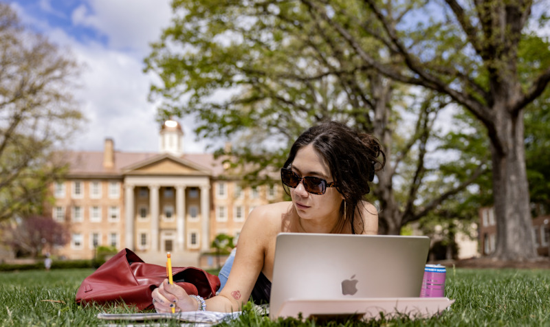 student works on laptop outside on UNC-Chapel Hill campus