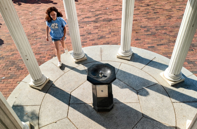 student walking up to old well