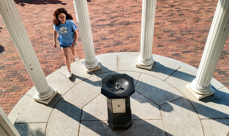 student walking up to old well