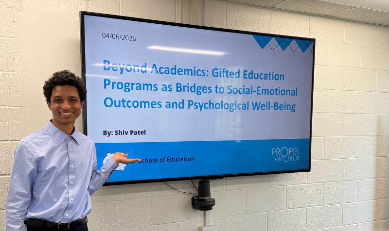 Shiv Patel poses with research presentation while defending his honors thesis