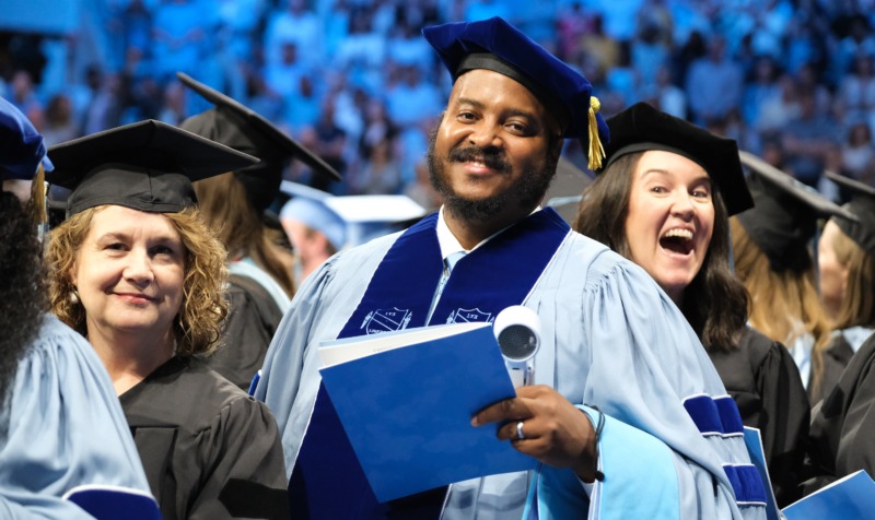 Doctoral students pose in crowd at graduation ceremony