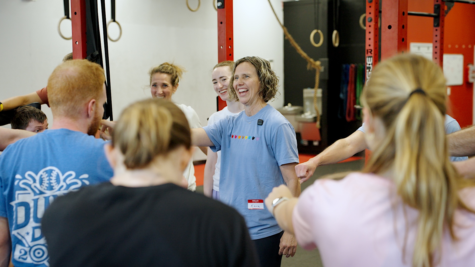 UNC School of Education faculty member Kara Hume stands smiling with a group of participants during an activity in a gym-like training space.