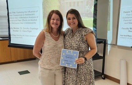 Meredith Marion posing with a certificate aside her mentor faculty member Dorothy Espelage