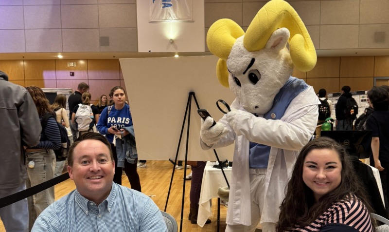 Casey Calhoun and graduate student pose for a photo with UNC-Chapel Hill mascot at the 2026 Research Fair.
