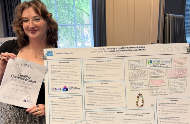Julia Fowlkes ('26 B.A.Ed.) poses with her search poster titled 