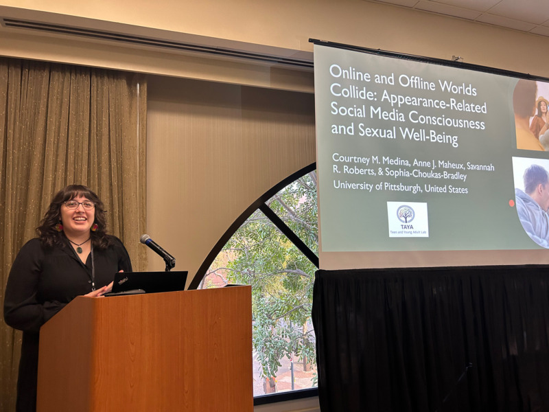 Courtney Medina presenting at a podium in front of a projector screen